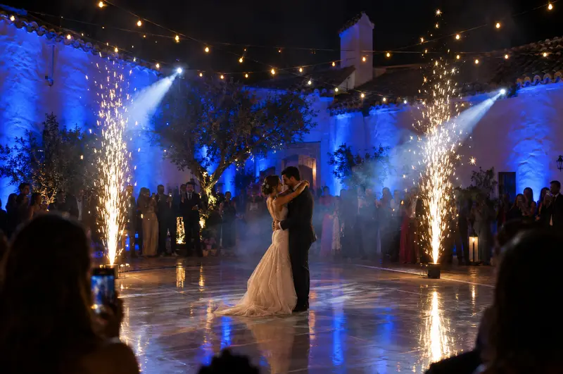Primer baile de una boda con chispas frías y luz azul en un cortijo